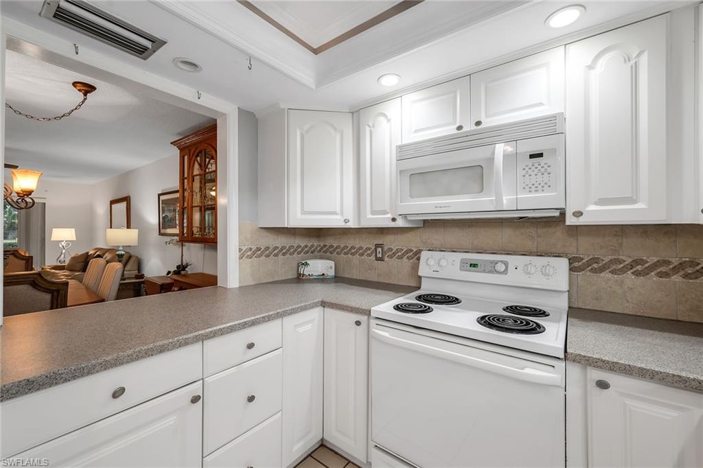 200 Valley Stream Drive, Unit 3B Naples, FL 34113 - Photo 7 of 45 a kitchen with granite countertop white cabinets and white appliances