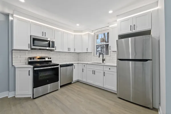 a kitchen with granite countertop white cabinets and stainless steel appliances