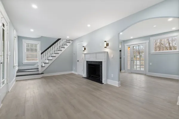 a view of an empty room with wooden floor fireplace and windows