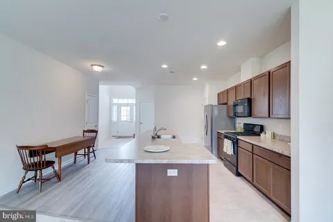 a kitchen with stainless steel appliances granite countertop a kitchen island hardwood floor sink stove dining table and chairs
