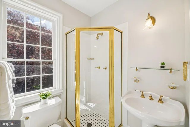 a view of a hallway with wooden floor and a bathroom
