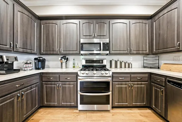 a kitchen with stainless steel appliances granite countertop a stove top oven a sink dishwasher and cabinets with wooden floor