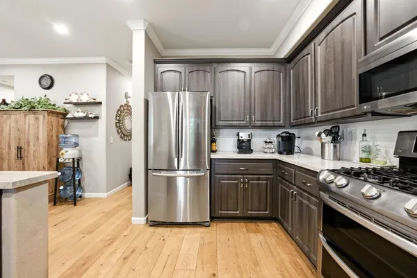 a kitchen with stainless steel appliances granite countertop a refrigerator a sink dishwasher a stove and a microwave oven with wooden floor