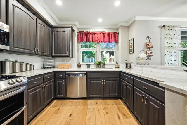 a kitchen with stainless steel appliances granite countertop wooden cabinets a sink dishwasher a stove and a refrigerator