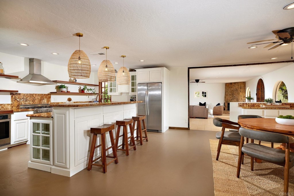 3182 Lone Jack Road Encinitas, CA 92024 - Photo 14 of 37 a kitchen with stainless steel appliances kitchen island a table chairs sink and cabinets