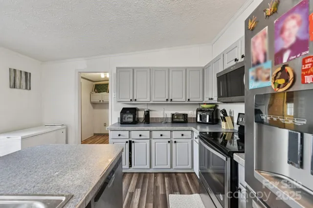 a kitchen with stainless steel appliances a stove top oven a sink a refrigerator white cabinets and wooden floor