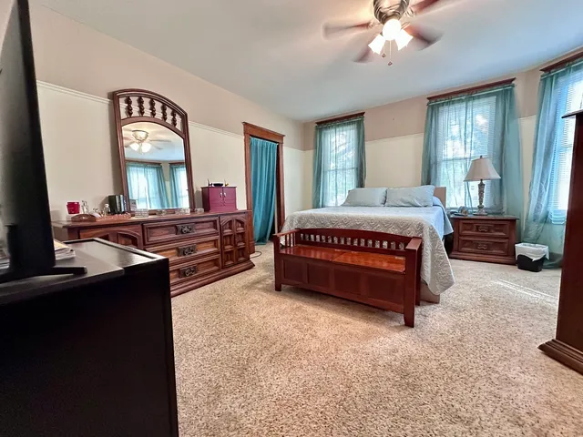 a spacious bedroom with a bed window and dresser