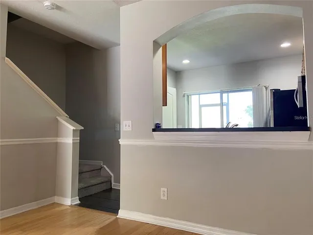 a view of a hallway to a room with wooden floor and staircase