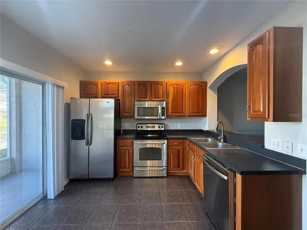a kitchen with stainless steel appliances granite countertop a refrigerator a stove a sink and a microwave