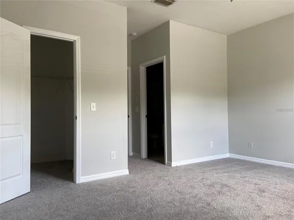 a view of an empty room with closet and a window