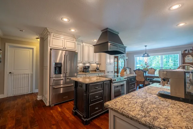 a kitchen with stainless steel appliances granite countertop a refrigerator a stove and a wooden floors