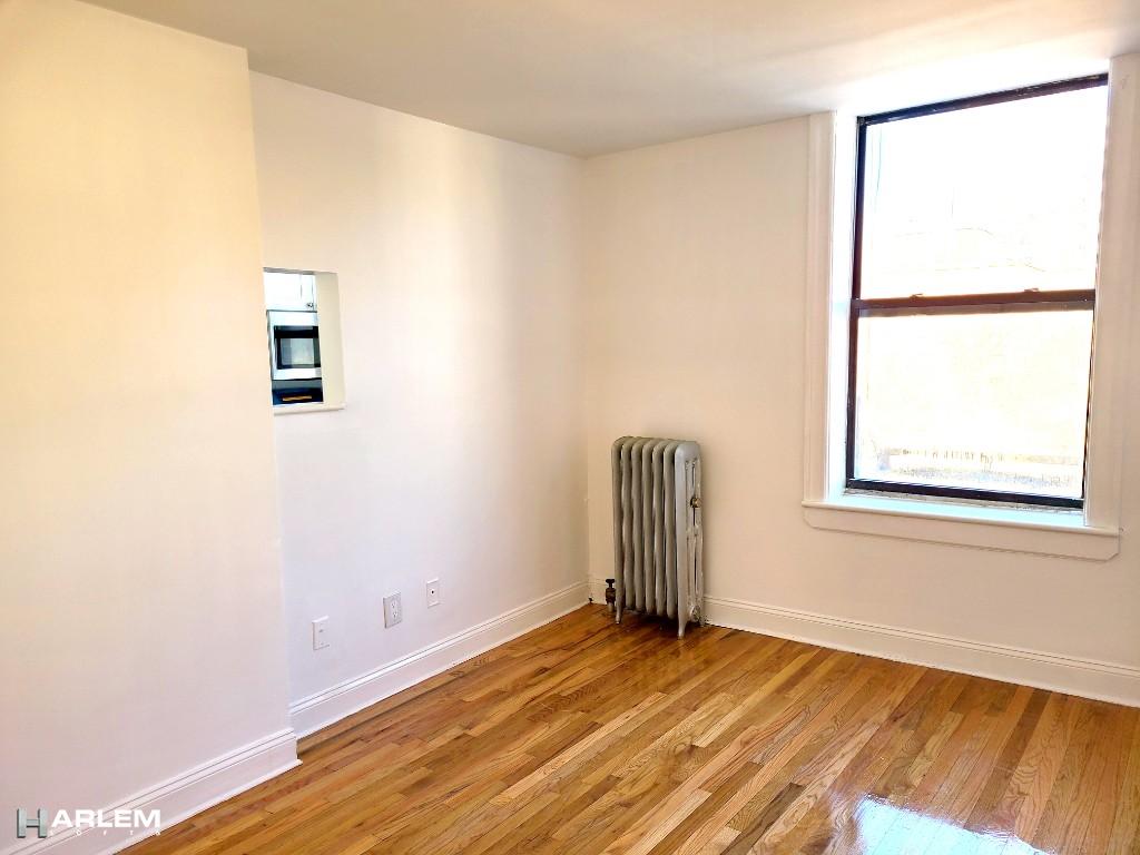 36 West 138th Street, Unit 52 Manhattan, NY 10037 - Photo 4 of 11 a view of an empty room with wooden floor and a window