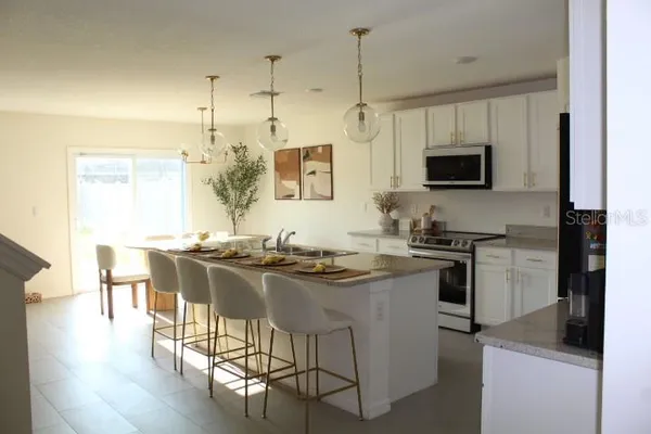 a kitchen with stainless steel appliances kitchen island granite countertop a sink and a stove top oven with wooden floor