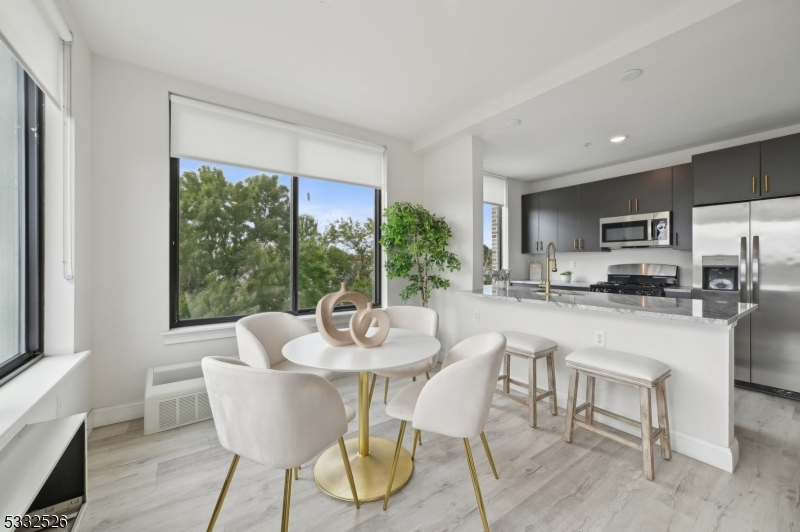 45 South Grove Street, Unit 232 East Orange, NJ 07018 - Photo 3 of 22 a dining room with furniture a large window and a kitchen view