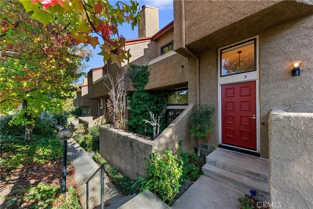 a view of a brick house with plants and wooden fence