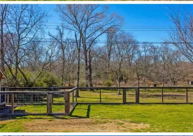 a view of swimming pool with lawn chairs and large trees