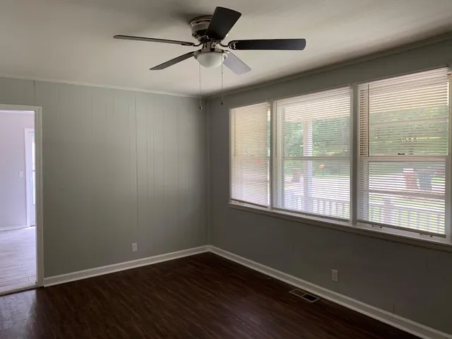 an empty room with wooden floor and windows