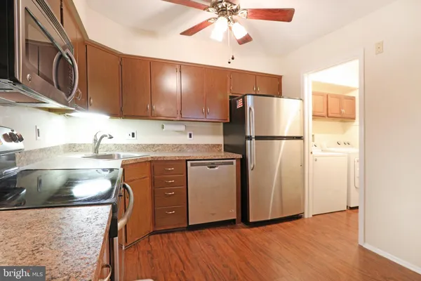 a kitchen with stainless steel appliances granite countertop a refrigerator a stove a sink and a microwave