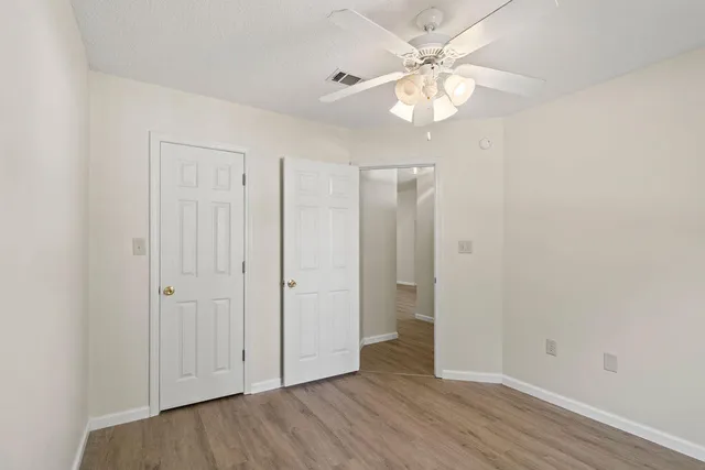 an empty room with wooden floor and a ceiling fan