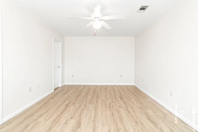 an empty room with a ceiling fan and wooden floor
