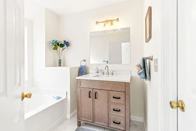 a bathroom with a tub sink and mirror