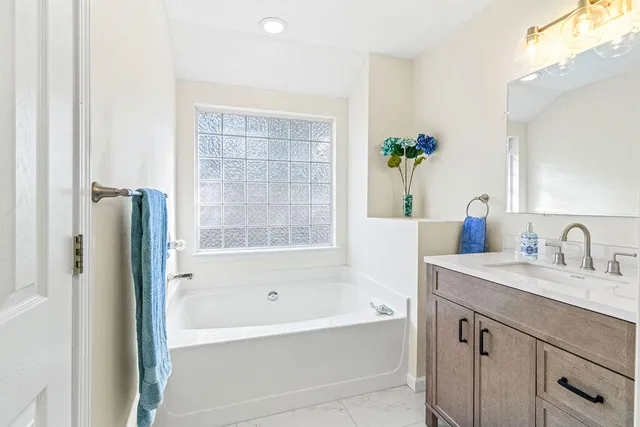 a bathroom with a tub sink and mirror