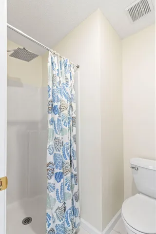 a white toilet sitting next to a shower curtain