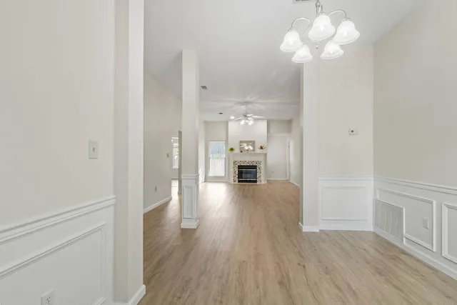 a view of a hallway with wooden floor and a chandelier