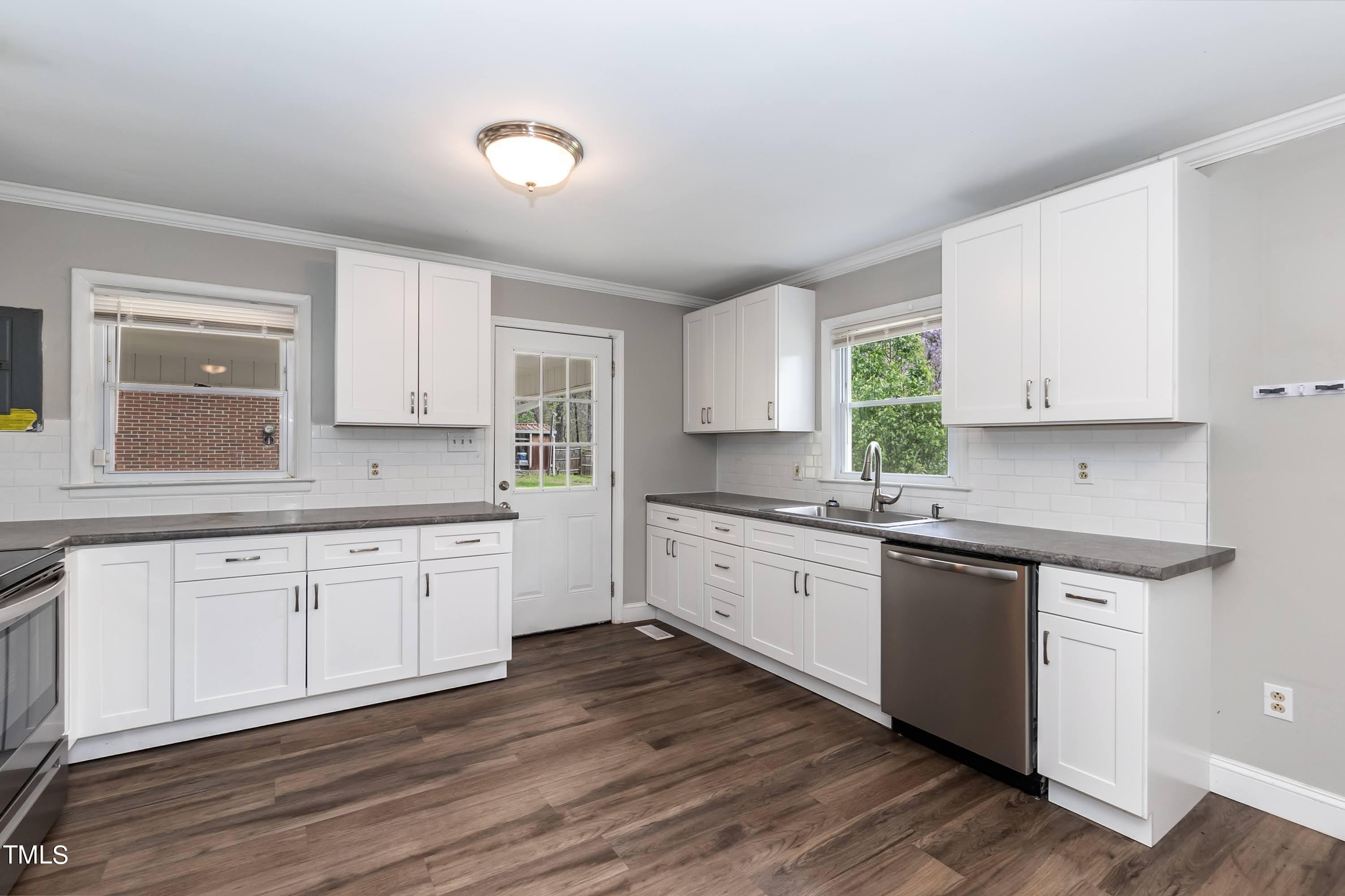 2019 Highway 55 Durham, NC 27707 - Photo 5 of 34 a large kitchen with granite countertop a stove top oven a sink and dishwasher with wooden floor