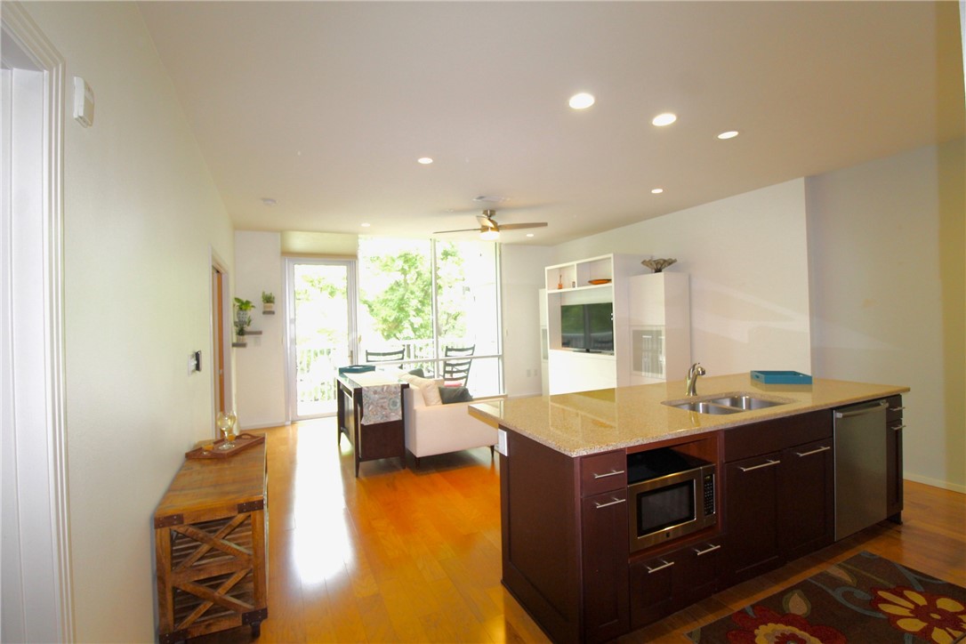 a living room with stainless steel appliances kitchen island granite countertop furniture and a large window