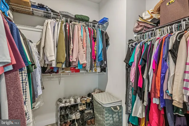 a view of walk in closet with clothes and shoes