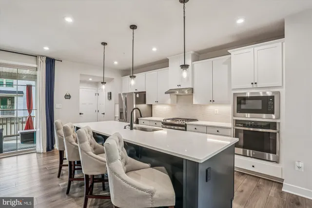 a kitchen with a stove a sink a kitchen island with chairs and wooden floor