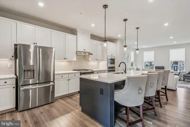 a kitchen with stainless steel appliances granite countertop a sink a stove a refrigerator and island with wooden floor