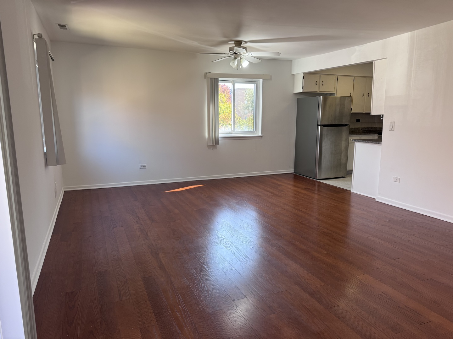 1785 West Algonquin Road, Unit 2A Mount Prospect, IL 60056 - Photo 4 of 14 an empty room with wooden floor a ceiling fan and windows
