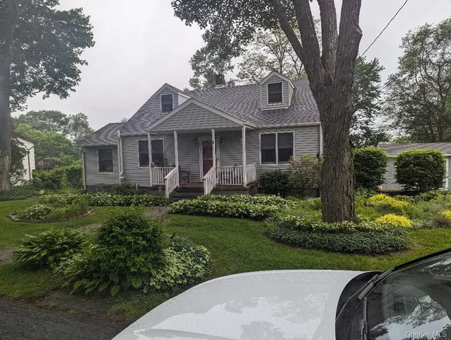 a front view of a house with a garden and trees