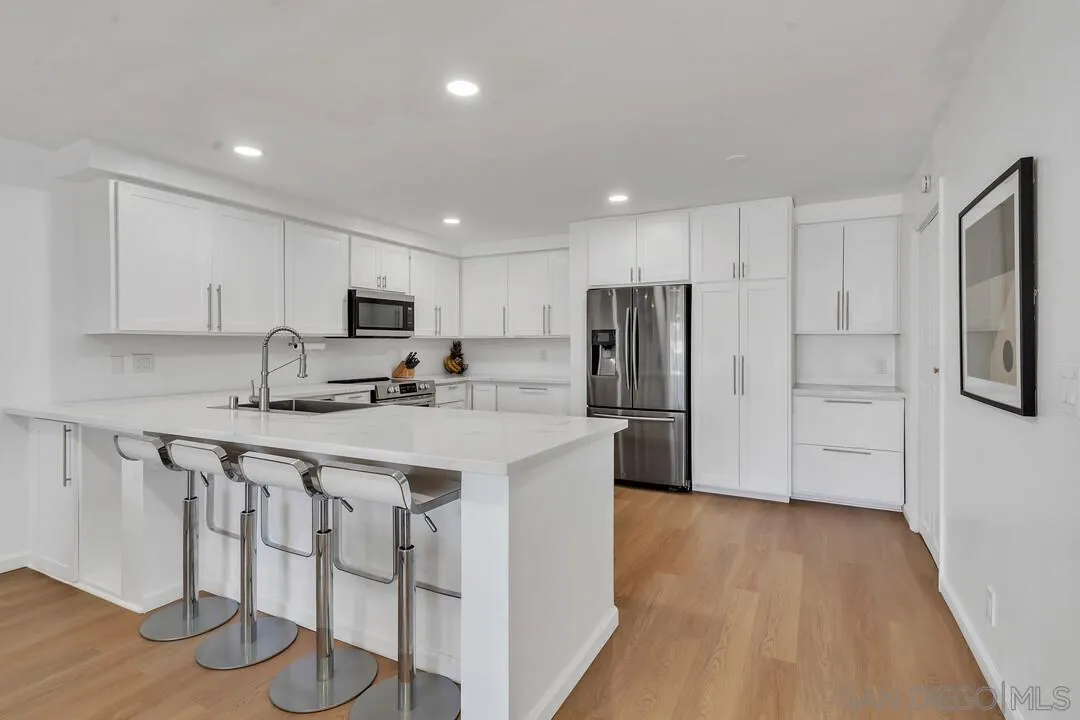 12027 Royal Road, Unit 3 El Cajon, CA 92021 - Photo 5 of 30 a kitchen with stainless steel appliances granite countertop a refrigerator sink and white cabinets