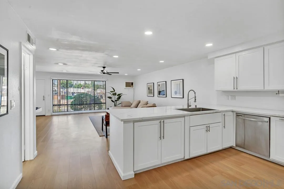12027 Royal Road, Unit 3 El Cajon, CA 92021 - Photo 7 of 30 a open kitchen with kitchen island a sink and white cabinets with wooden floor