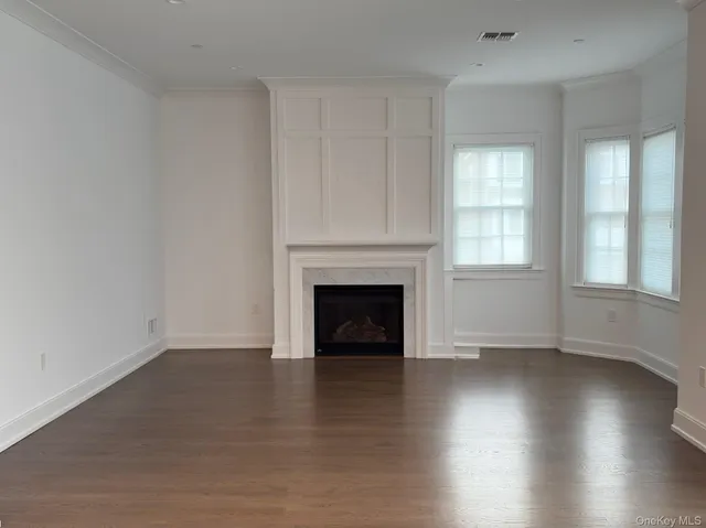 an empty room with wooden floor fireplace and windows