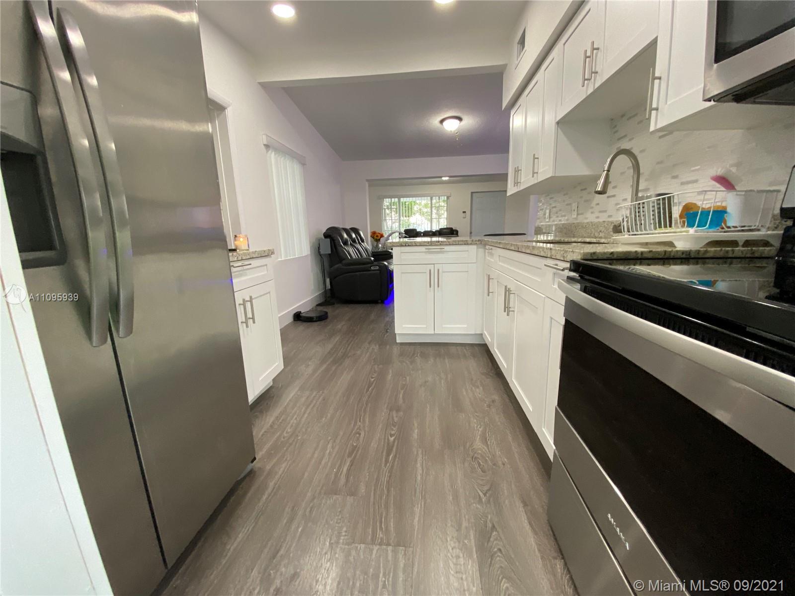 2380 Service Road Opa-Locka, FL 33054 - Photo 14 of 22 a kitchen with stainless steel appliances a refrigerator a sink and white cabinets