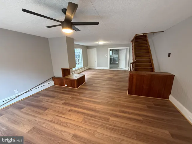 a view of a livingroom with wooden floor and a ceiling fan