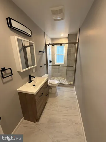 a bathroom with a sink a toilet a mirror and shower