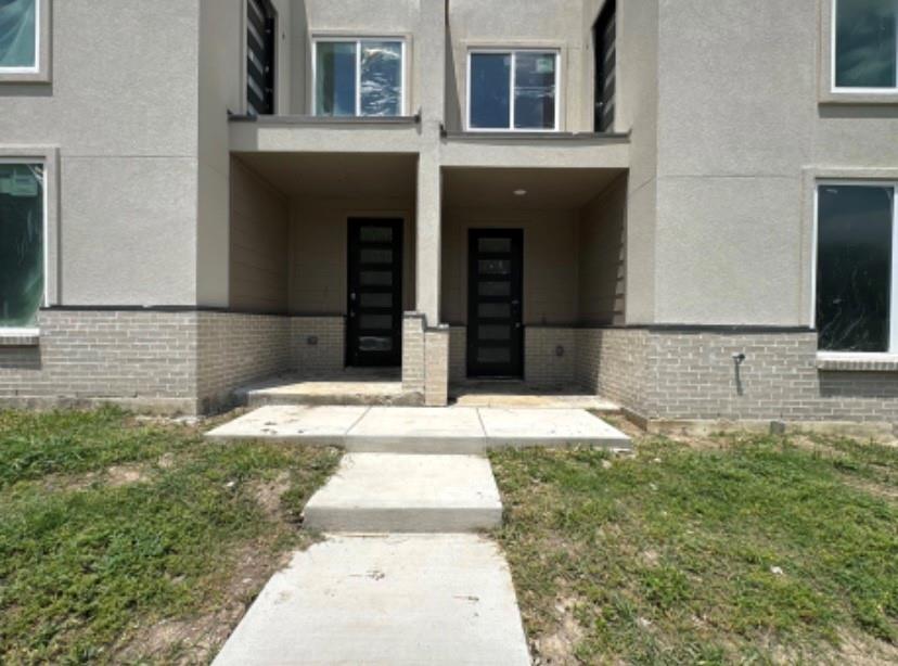 9475 Timberleaf Drive Dallas, TX 75243 - Photo 20 of 23 Property entrance with brick siding, stucco siding, and a lawn