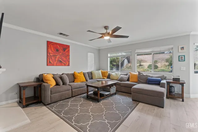 a living room with furniture ceiling fan and a large window