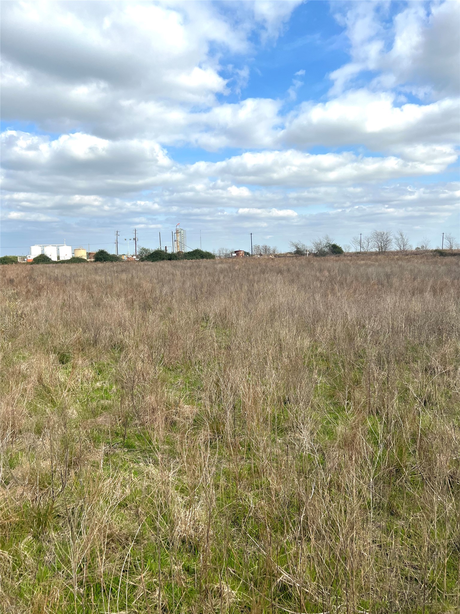 Tbd Lot 2 Tbd Road Eagle Lake, TX 77434 - Photo 13 of 24 Expansive open land featuring natural grasses and distant structures under a clear sky with scattered clouds