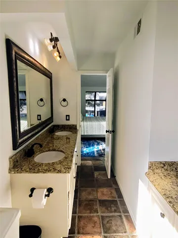 a view of a lake with lawn chairs and large trees