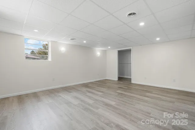 an empty room with wooden floor and natural light