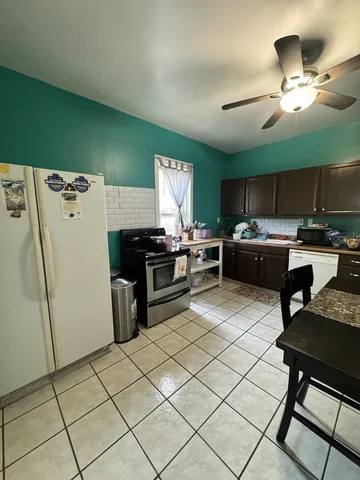 a dining room with furniture and a chandelier fan
