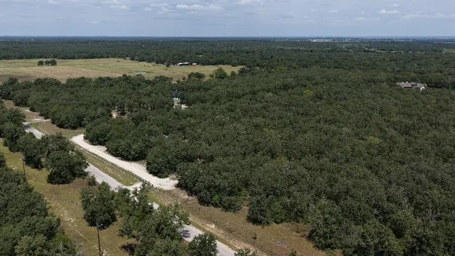 an aerial view of field with trees in back