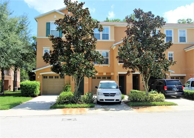 a front view of a house with a garden and tree