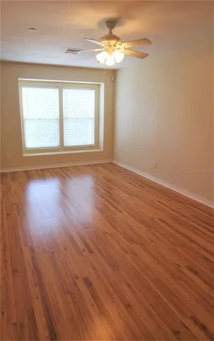 a view of an empty room with wooden floor and a window